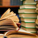 Pile of open books on table in front of book case