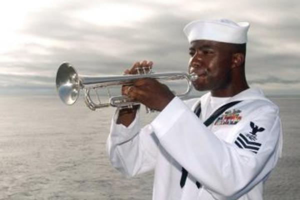 A man in a sailor's uniform playing the bugle