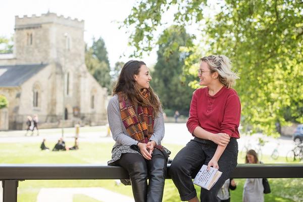 Students sat on fence in front of church and lawn