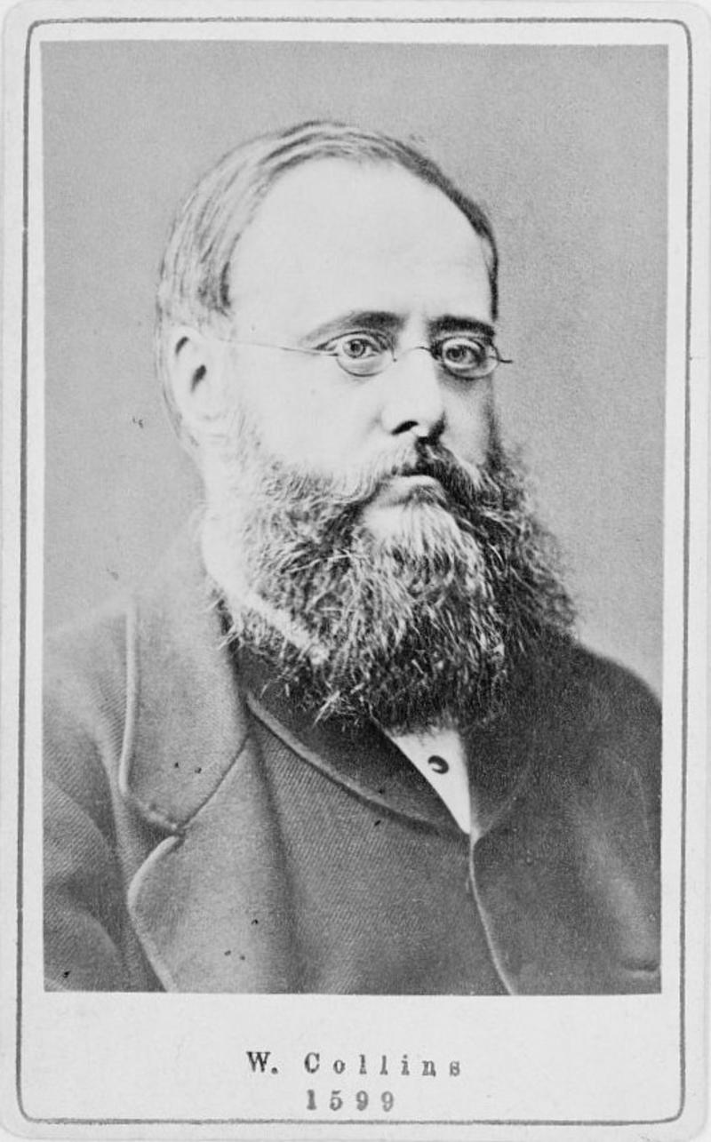 A black and white photographic portrait of Wilkie Collins, British author, head-and-shoulders portrait, facing right.