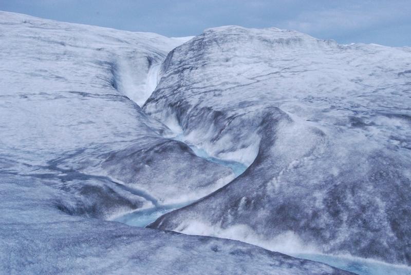Blue meltwater cuts a jagged path through an icy landscape
