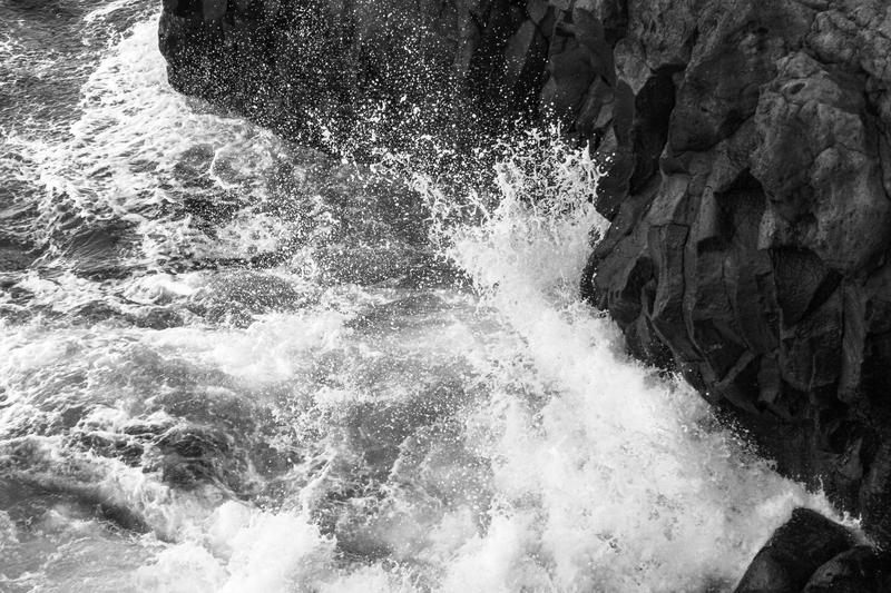 A black and white image of waves crashing on rocks