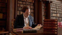 Dr Michael Sullivan sat in library examining book