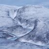 Blue meltwater cuts a jagged path through an icy landscape